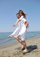 feliz pareja joven divertirse en la playa foto