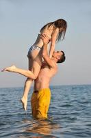 feliz pareja joven divertirse en la playa foto