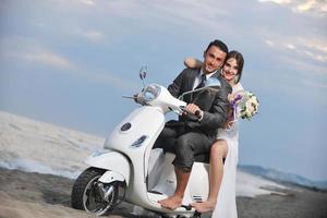 just married couple on the beach ride white scooter photo