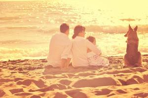 happy family playing with dog on beach photo