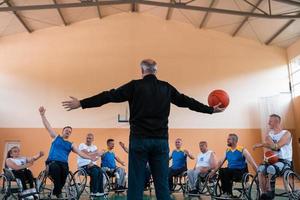 the selector of the basketball team with a disability stands in front of the players and shows them the stretching exercises before the start of training photo