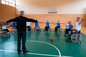 the selector of the basketball team with a disability stands in front of the players and shows them the stretching exercises before the start of training photo