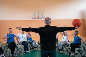 the selector of the basketball team with a disability stands in front of the players and shows them the stretching exercises before the start of training photo