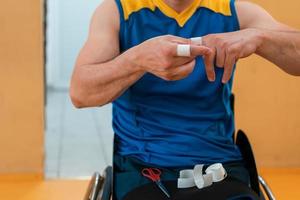 a disabled basketball player puts on a corset and bandages on his arms and fingers in preparation for a game in the arena photo