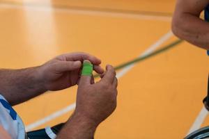 a disabled basketball player puts on a corset and bandages on his arms and fingers in preparation for a game in the arena photo