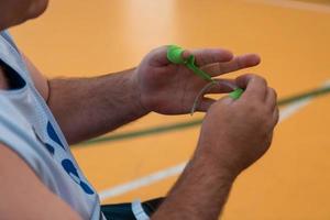 un jugador de baloncesto discapacitado se pone un corsé y se venda los brazos y los dedos para prepararse para un partido en la arena foto