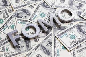 The word FOMO laid with aluminium letters on the US dollar banknotes background - with selective focus photo