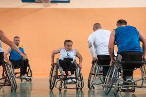 Disabled War veterans mixed race and age basketball teams in wheelchairs playing a training match in a sports gym hall. Handicapped people rehabilitation and inclusion concept photo