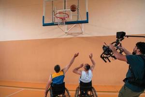 un camarógrafo con equipo profesional graba un partido de la selección nacional en silla de ruedas jugando un partido en la arena foto