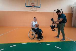 un camarógrafo con equipo profesional graba un partido de la selección nacional en silla de ruedas jugando un partido en la arena foto