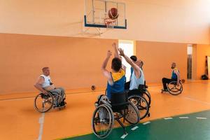 Disabled War veterans mixed race and age basketball teams in wheelchairs playing a training match in a sports gym hall. Handicapped people rehabilitation and inclusion concept photo