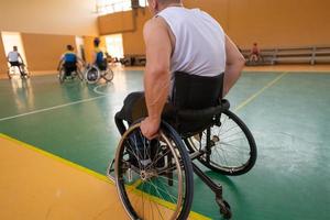 Disabled War veterans mixed race and age basketball teams in wheelchairs playing a training match in a sports gym hall. Handicapped people rehabilitation and inclusion concept photo