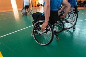 Close up photo of wheelchairs and handicapped war veterans playing basketball on the court