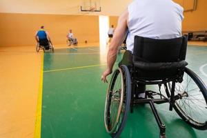 Close up photo of wheelchairs and handicapped war veterans playing basketball on the court