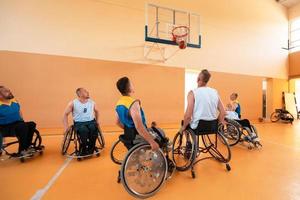 Disabled War veterans mixed race and age basketball teams in wheelchairs playing a training match in a sports gym hall. Handicapped people rehabilitation and inclusion concept photo