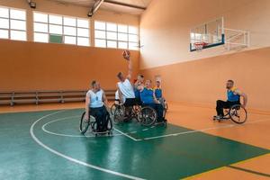 Disabled War veterans mixed race and age basketball teams in wheelchairs playing a training match in a sports gym hall. Handicapped people rehabilitation and inclusion concept photo