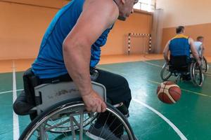 Disabled War veterans mixed race and age basketball teams in wheelchairs playing a training match in a sports gym hall. Handicapped people rehabilitation and inclusion concept photo