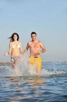 feliz pareja joven divertirse en la playa foto