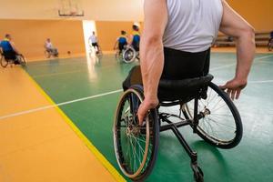 Close up photo of wheelchairs and handicapped war veterans playing basketball on the court