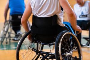 Close up photo of wheelchairs and handicapped war veterans playing basketball on the court