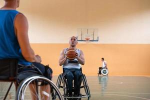 veteranos de guerra discapacitados en sillas de ruedas con equipo profesional juegan un partido de baloncesto en la sala. el concepto de deportes con discapacidad foto