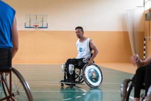 veteranos de guerra discapacitados de raza mixta que se oponen a equipos de baloncesto en sillas de ruedas fotografiados en acción mientras juegan un partido importante en una sala moderna. foto