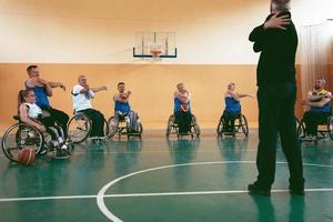 the selector of the basketball team with a disability stands in front of the players and shows them the stretching exercises before the start of training photo