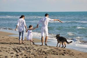 familia feliz jugando con el perro en la playa foto