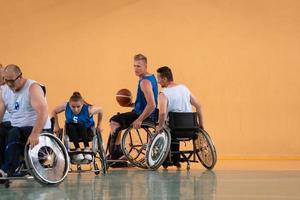 veteranos de guerra discapacitados de raza mixta que se oponen a equipos de baloncesto en sillas de ruedas fotografiados en acción mientras juegan un partido importante en una sala moderna. foto