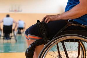 Close up photo of wheelchairs and handicapped war veterans playing basketball on the court