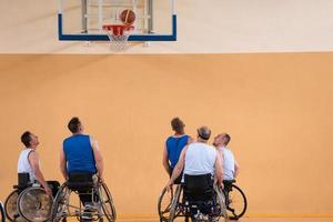 Disabled War veterans mixed race opposing basketball teams in wheelchairs photographed in action while playing an important match in a modern hall. photo