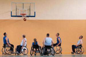 Disabled War veterans mixed race opposing basketball teams in wheelchairs photographed in action while playing an important match in a modern hall. photo