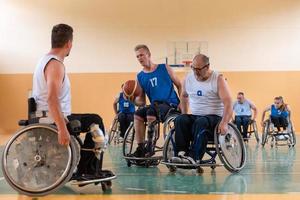 Disabled War veterans mixed race opposing basketball teams in wheelchairs photographed in action while playing an important match in a modern hall. photo