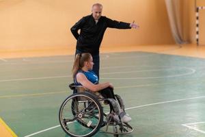 a sports basketball coach explains to a disabled woman in a wheelchair which position to play during a game photo