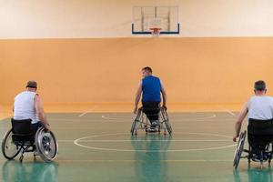 veteranos de guerra discapacitados de raza mixta que se oponen a equipos de baloncesto en sillas de ruedas fotografiados en acción mientras juegan un partido importante en una sala moderna. foto