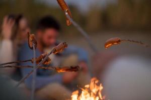 grupo de jóvenes amigos sentados junto al fuego en la playa foto