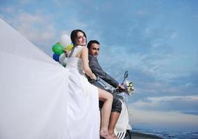 just married couple on the beach ride white scooter photo