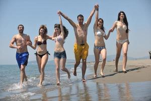 grupo de gente feliz divertirse y correr en la playa foto