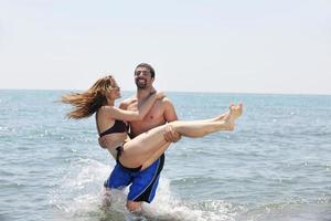 feliz pareja joven divertirse en la playa foto