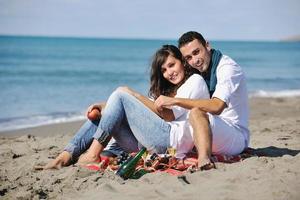 pareja joven disfrutando de un picnic en la playa foto