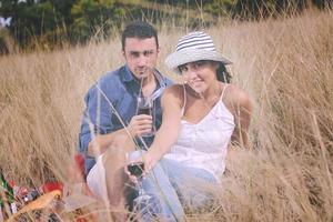 pareja feliz disfrutando de un picnic en el campo en hierba larga foto