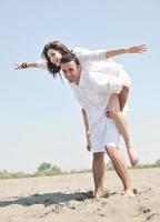 feliz pareja joven divertirse en la playa foto