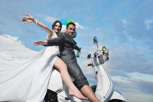 just married couple on the beach ride white scooter photo