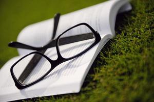 Glasses on a book outside with grass photo