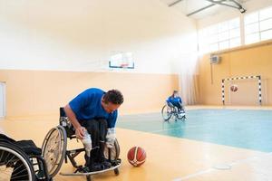 un jugador de baloncesto discapacitado se prepara para un partido mientras está sentado en una silla de ruedas. preparativos para un partido de baloncesto profesional. el concepto de deporte para discapacitados foto