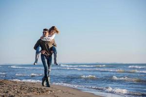 pareja divirtiéndose en la playa durante el otoño foto