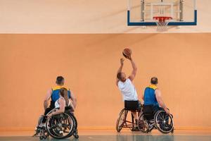 Disabled War veterans mixed race and age basketball teams in wheelchairs playing a training match in a sports gym hall. Handicapped people rehabilitation and inclusion concept photo