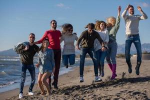 young friends jumping together at autumn beach photo