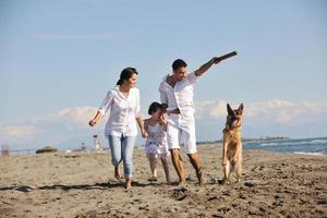 familia feliz jugando con el perro en la playa foto