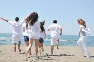 grupo de gente feliz divertirse y correr en la playa foto